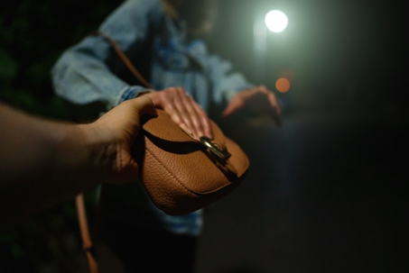 Thief snatches bag from woman on the night street.